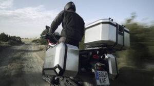 Vídeo promocional aspiracional. Moto des de darrera corrent pel camp amb maletes Shad Terra